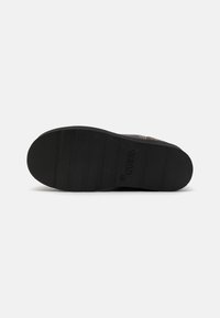 Suola di sneakers in gomma nera con texture rigata, caratterizzata da un logo e un profilo piatto. Progettata per grip e durata.