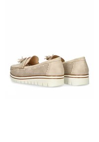 Los zapatos de ante beige presentan un diseño perforado, borlas decorativas y una suela gruesa blanca con una línea de acento marrón.