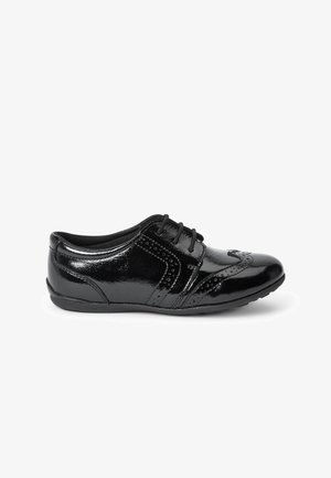 Scarpa in vernice nera con punta arrotondata, decorazioni tipo brogue, design con lacci e suola in gomma bassa. Texture liscia con un leggero lucido.