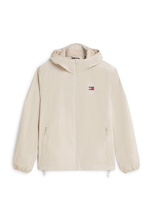 Beige hættetrøje med lynlås, elastiske manchetter, lynlåslommer foran og lille rektangulært logo på brystet.