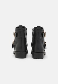 Botas de baile de cuero negro con una resistente suela de goma, con acentos dorados y cremalleras laterales para un uso fácil.