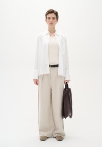 Vit skjorta med knäppning, beige linnevidbyxor, svart bälte, neutral linne-topp, brun läderväska och beiga skor. Minimalistisk design.