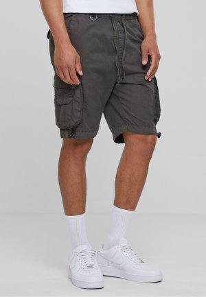 Cargo shorts in dark gray fabric, featuring side pockets, adjustable hems, and a drawstring waistband. Paired with white sneakers and socks.