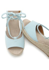 Svetlo modre espadrile s sandali z zgornjim delom iz blaga, odprto konico, vezanjem okrog gležnja in klinastim peto ovitim z juto. Mehka podloga iz usnja.