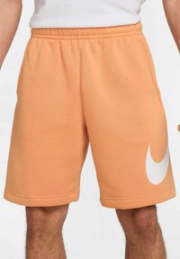 Shorts de mezcla de algodón en color naranja con una cintura elástica y bolsillos laterales. Presenta un gran logo blanco de Nike en la pierna izquierda.