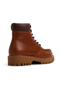 Botas de cuero hasta el tobillo en marrón con un cuello acolchado en marrón oscuro, parte frontal con cordones y suela de goma gruesa con un patrón de tacos robusto.