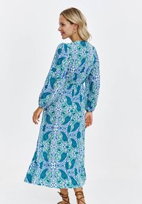 Sukienka z długim rękawem w niebiesko-zielony wzór paisley. Wykonana z lekkiego materiału, charakteryzuje się zwiewną sylwetką i spódnicą o długości midi.
