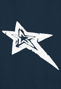 Tissu bleu marine présentant un grand motif d'étoile blanche avec une texture vieillie et des bords nets, centré et légèrement incliné vers la droite.