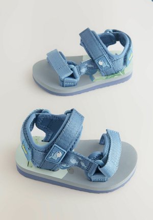 Sandales bleues pour enfants avec des sangles en tissu ajustables, une semelle en caoutchouc texturée et une semelle intérieure à motifs présentant des designs aquatiques.