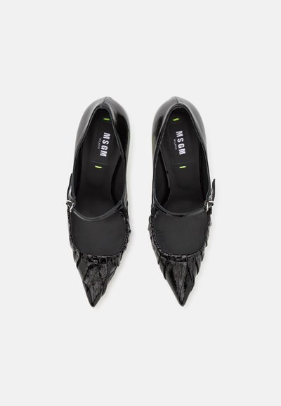 Black pointed-toe shoes with a textured finish, featuring a strap and buckle detail, smooth interior, and branding on the insole.