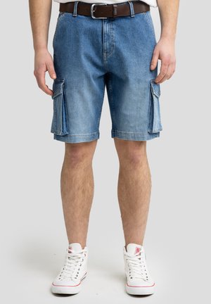 Denim cargo shorts, lys blå vask, løs pasform, med sidelommer. Sammen med hvide sneakers, prydet med et struktureret brunt bælte.