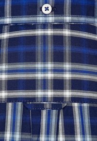 Tessuto a quadri blu navy e blu con strisce bianche, caratterizzato da un dettaglio con bottone in alto e un design con orlo piegato. Materiale in cotone strutturato.