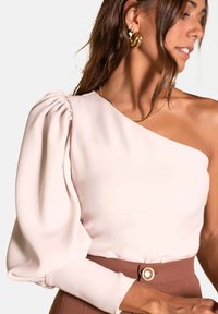 Blusa de un solo hombro en suave tela rosa con una manga abullonada. Presenta un corsé ajustado y un cinturón de tiro alto en marrón contrastante con un botón.