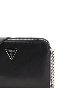 Borsa in pelle nera con hardware argentato, chiusura con zip e tracolla a catena. Presenta un logo triangolare GUESS in argento sulla parte anteriore.