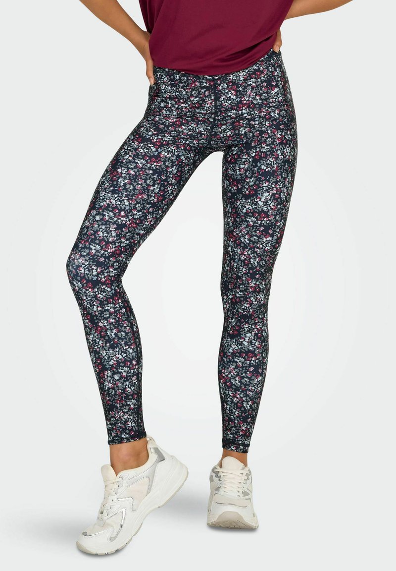 Blommiga leggings med en mörk marinblå bakgrund, prydda med små rosa och vita blommor. Tillverkade av elastiskt tyg, designade för aktiv användning.