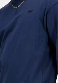 Sudadera azul marino con puños y cuello acanalados. Presenta un sutil logo bordado en el pecho y una textura de tejido suave.