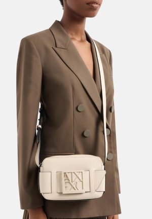Borsa a tracolla in pelle beige con design strutturato, logo impresso e tracolla regolabile. Accenti testurizzati aumentano l'interesse visivo.
