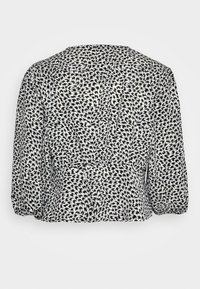 Blusa em preto e branco com um padrão em espiral, decote redondo e mangas a três quartos com um detalhe ligeiramente franzido na cintura.