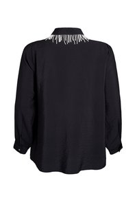 Blusa nera a maniche lunghe con tessuto texturizzato e dettagli di frange di perline bianche lungo il colletto posteriore.