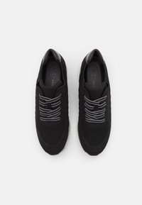 Sneaker nere con un upper in maglia strutturata, design con lacci e lacci riflettenti, e un accento sul tallone nero liscio.