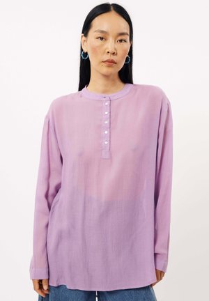 Lila Langarmshirt mit rundem Ausschnitt, ausgestattet mit einer Knopfleiste und aus einem strukturierten, leichten Stoff. Lässige Passform und subtiler Glanz.