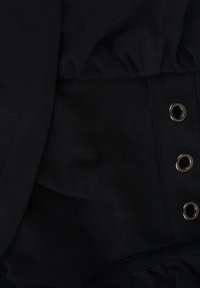 Vêtement en tissu noir présentant un design froncé, des œillets en métal et une ceinture élastique. Texture lisse avec une finition mate.