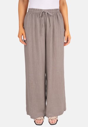 Pantalon large en lin taupe pour femme avec taille élastique et cordon de serrage, associé à des sandales beiges à bouts ouverts et un haut blanc.