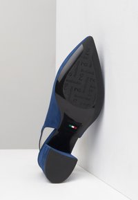 Navyblaue Wildleder-Pumps mit einer runden Fußspitze und einem Ausschnittdesign. Die schwarze Sohle bietet geprägte Markenkennzeichnung und ein italienisches Flaggenakzent.