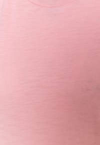 Ljusrosa t-shirt med kort ärm, tillverkad av mjukt, något texturerat tyg. Har en rund halsringning och en slät yta utan mönster.