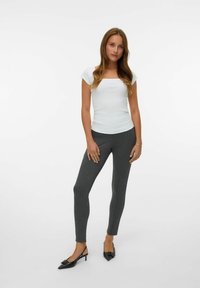 Top blanco de cuello cuadrado con mangas cortas, combinado con pantalones de rayas grises oscuros y tacones negros de punta. Tejido liso y diseño ajustado.