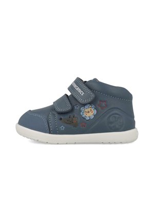 Zapato para niño pequeño de color azul oscuro con suela blanca, dos tiras de velcro y diseños de dibujos animados de una flor sonriente y un perro con estrellas.