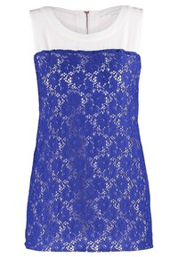 Top in pizzo blu con un pannello di tessuto bianco nella scollatura. Presenta un motivo floreale in pizzo e una cerniera sul retro per la chiusura.
