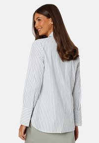 Camicia a righe con maniche lunghe, tessuto leggero, strisce verticali verdi e bianche, design sartoriale, orlo arrotondato, polsini con bottoni.