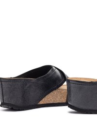 Sandales compensées en cuir noir avec une semelle en liège, présentant un design de bandes croisées et une surface texturée pour une meilleure adhérence. Talon bas.