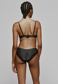 Zwart lingerie set met een gestructureerde beha met verstelbare bandjes en bijpassende bikini-stijl onderbroek met kantafwerking.