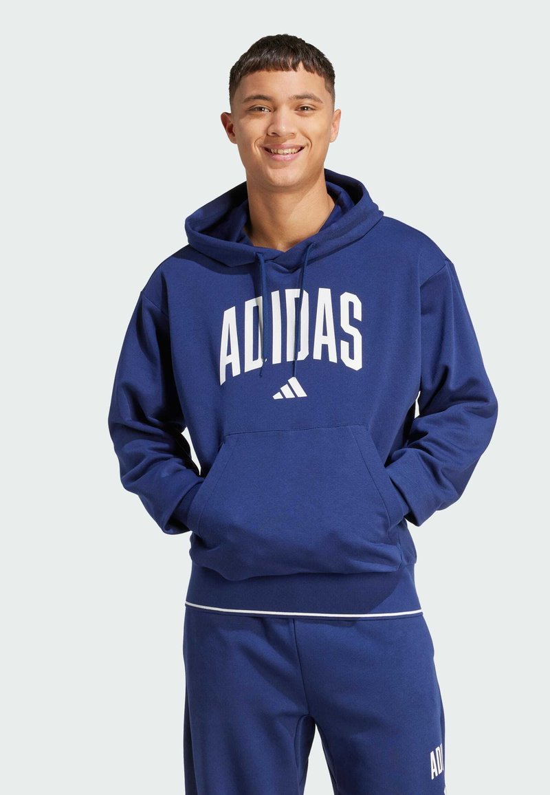 Mörkblå hoodie i mjukt material med en känguruficka, justerbar dragsko och vit "ADIDAS"-logotyp på framsidan.