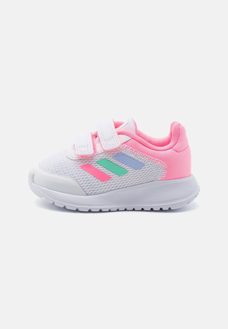White athletic shoe with pink accents, mesh upper, and Velcro straps. Features three horizontal stripes in pink, light blue, and green.