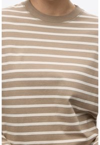 Camiseta de manga larga a rayas marrones y blancas, hecha de algodón suave, con cuello redondo y un corte holgado. Sin logotipos ni adornos visibles.