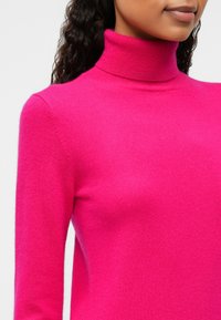 Fuchsia turtleneck sweater made of smooth knit fabric, featuring long sleeves and a fitted silhouette.