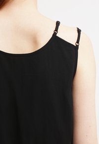 Czarny bezrękawnik z regulowanymi ramiączkami, okrągłym dekoltem i gładką fakturą. Posiada minimalne detale na plecach.