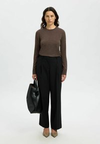 Pantaloni neri su misura, camicia lunga marrone, borsa a tracolla nera e tacchi beige a punta. Tessuti lisci e design strutturato.