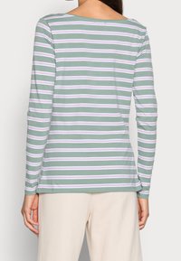 Langarmshirt aus grüner Baumwolle mit lavendelfarbenen und weißen horizontalen Streifen, das einen weiten Ausschnitt und eine glatte Textur aufweist.