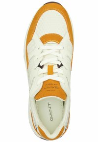 Weiße Sneakers mit orangen Wildlederakzenten und Mesh-Gewebe. Sie verfügen über eine flache weiße Schnürung, eine gepolsterte Zunge und ein Logo auf der Innensohle.