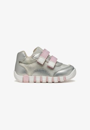 Zapatillas infantiles metálicas plateadas con correas de velcro rosas, suelas blancas y acabado texturizado. Cuentan con puntera redondeada y cuello acolchado.