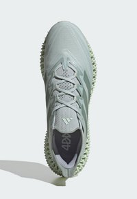 Lichtgroene sportschoen met een textuur van mesh bovenkant, opvallend vetersysteem en unieke spikes onderkant voor grip.