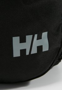 Borsa in tessuto nero con logo "HH" grigio chiaro. La texture è liscia con un sottile motivo a trama, che enfatizza la durata e il design.