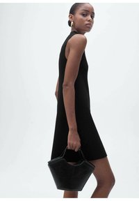 Black sleeveless dress with a fitted design, paired with a black structured handbag. Smooth texture and minimalist aesthetic.