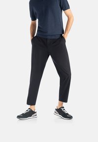 Námořnické tričko s krátkým rukávem, černé zúžené kalhoty a černé tenisky se šedými akcenty a bílými tkaničkami, zobrazené na bílém pozadí.