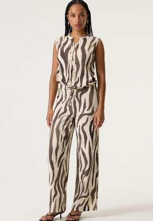 Mono estampado beige y marrón con parte superior sin mangas, cierre de botones y pantalones de pierna ancha, con un detalle de cinturón anudado.