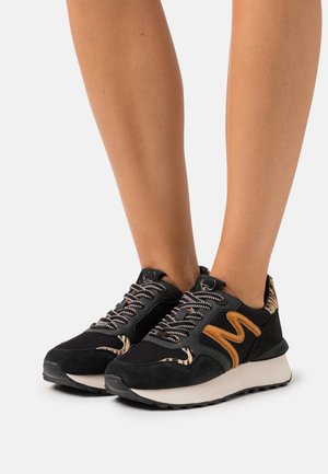 Black and brown athletic shoes with mesh and suede materials, featuring a curved design, textured accents, and patterned detailing on the sides.